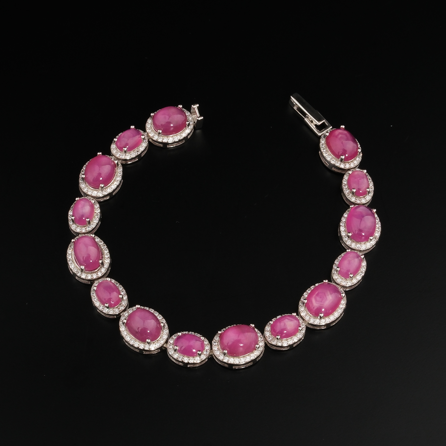 bracciale-argento-rubino-naturale-donna-lusso Bracciale lussuoso in argento sterling 925 da donna con rubini rosso-rosa taglio cabochon racchiusi in cornici ovali di zirconi, mostrato in 1.jpg.