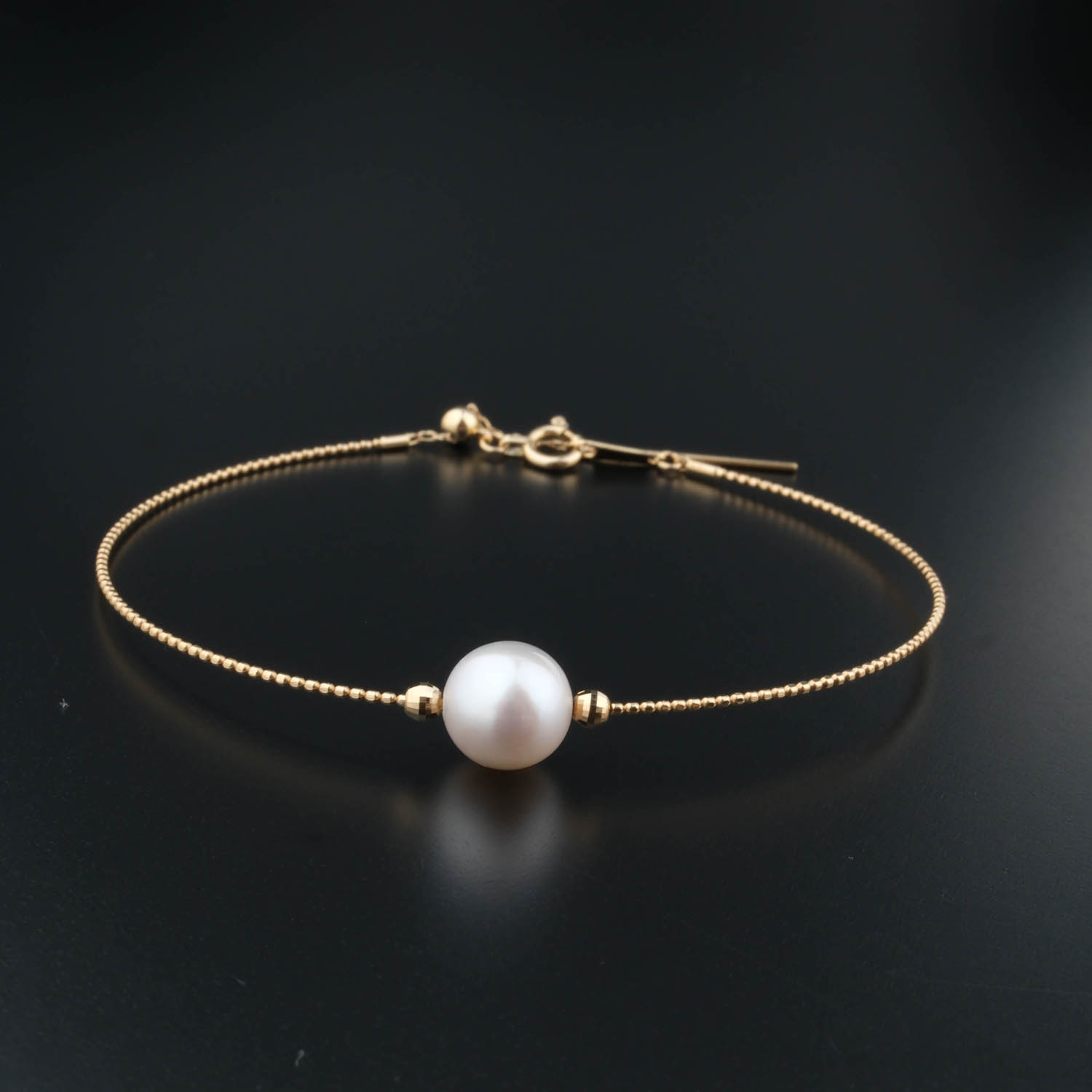 bracciale-oro-perla-design Bracelet délicat en chaîne en or 18k avec une perle blanche originale au centre.