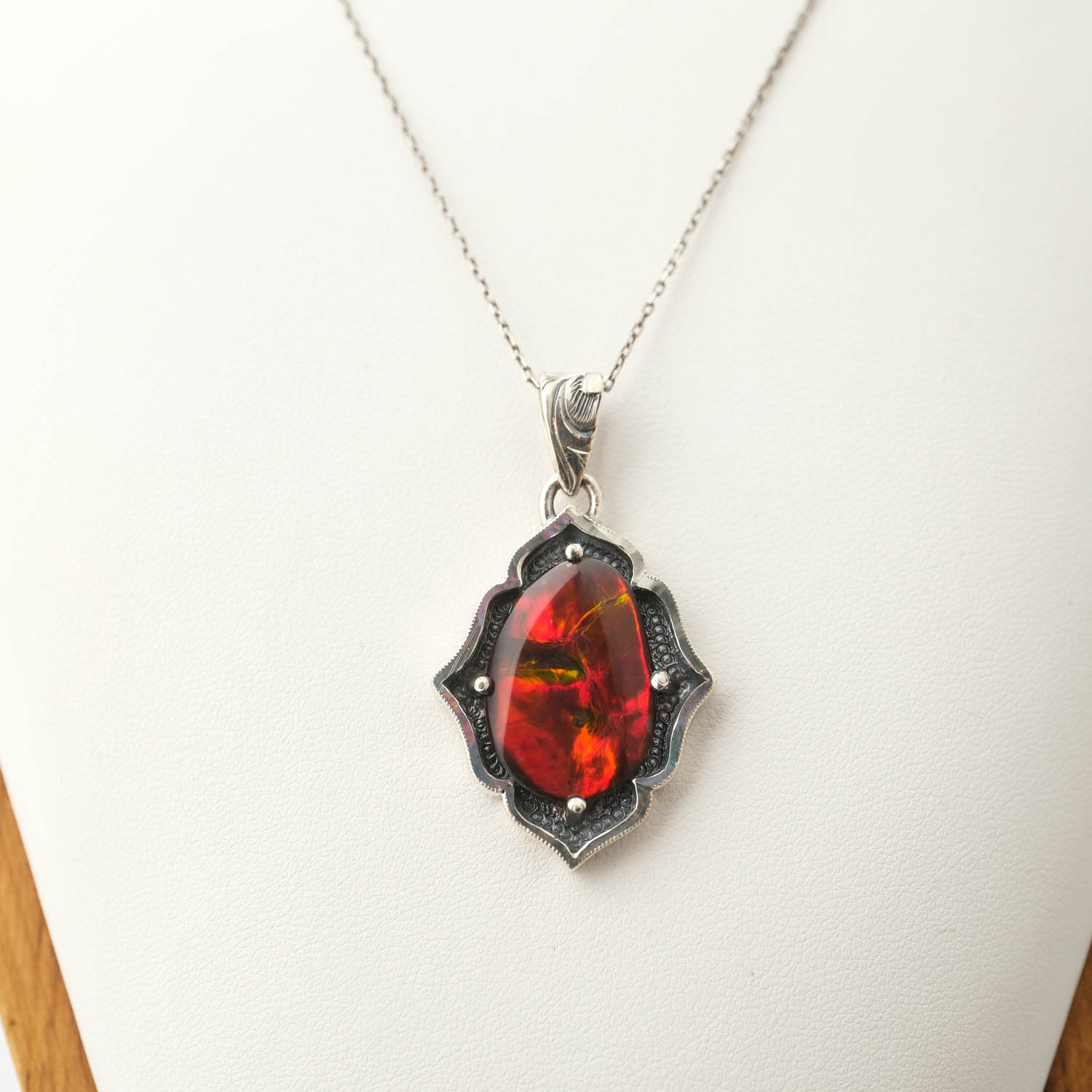 collana-argento-fatta-a-mano-opale-ammonite-bodrial 925 sterling silver necklace featuring an original ammonite bodrial opal natural stone with red and green fiery flashes and detailed handcrafted motifs.