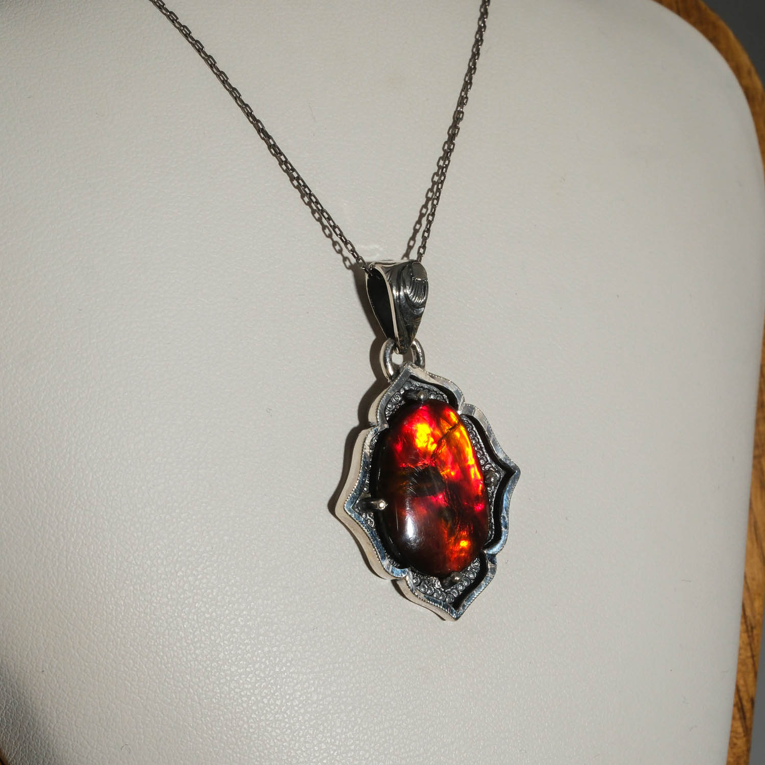 collar-plata-hecho-a-mano-opalo-ammonite-bodrial Collier en argent 925 orné d'une pierre naturelle d'opale ammonite bodrial originale avec des reflets ardents rouges et verts et des motifs détaillés faits à la main.