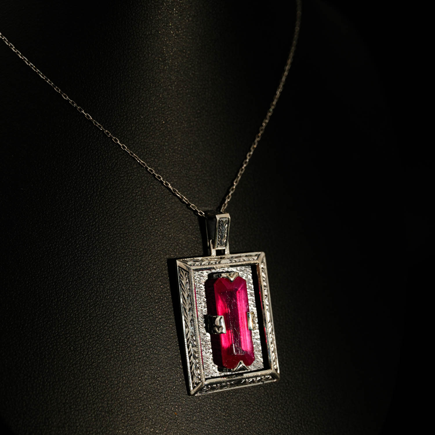 collar-plata-hecho-a-mano-rubi-diseno-rectangular 925 sterling silver necklace featuring a rectangular facet cut original ruby natural stone in a rectangular frame with handcrafted floral motifs.