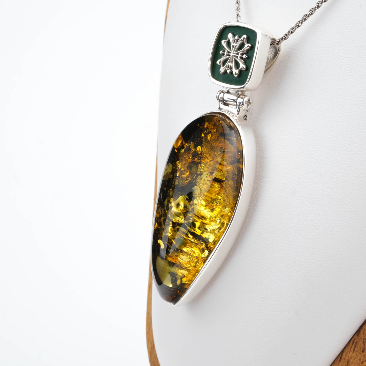 collier-argent-ambre-goutte-de-collection Collectible handcrafted 925 sterling silver necklace with a teardrop-shaped original natural amber stone, decorated with dark green enamel work and elegant silver motifs.