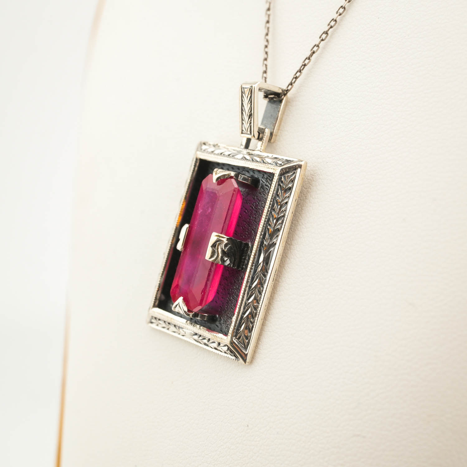 collier-argent-fait-main-rubis-design-rectangulaire Collier en argent 925 orné d'une pierre naturelle de rubis original de taille facette rectangulaire dans un cadre rectangulaire avec des motifs floraux faits à la main.