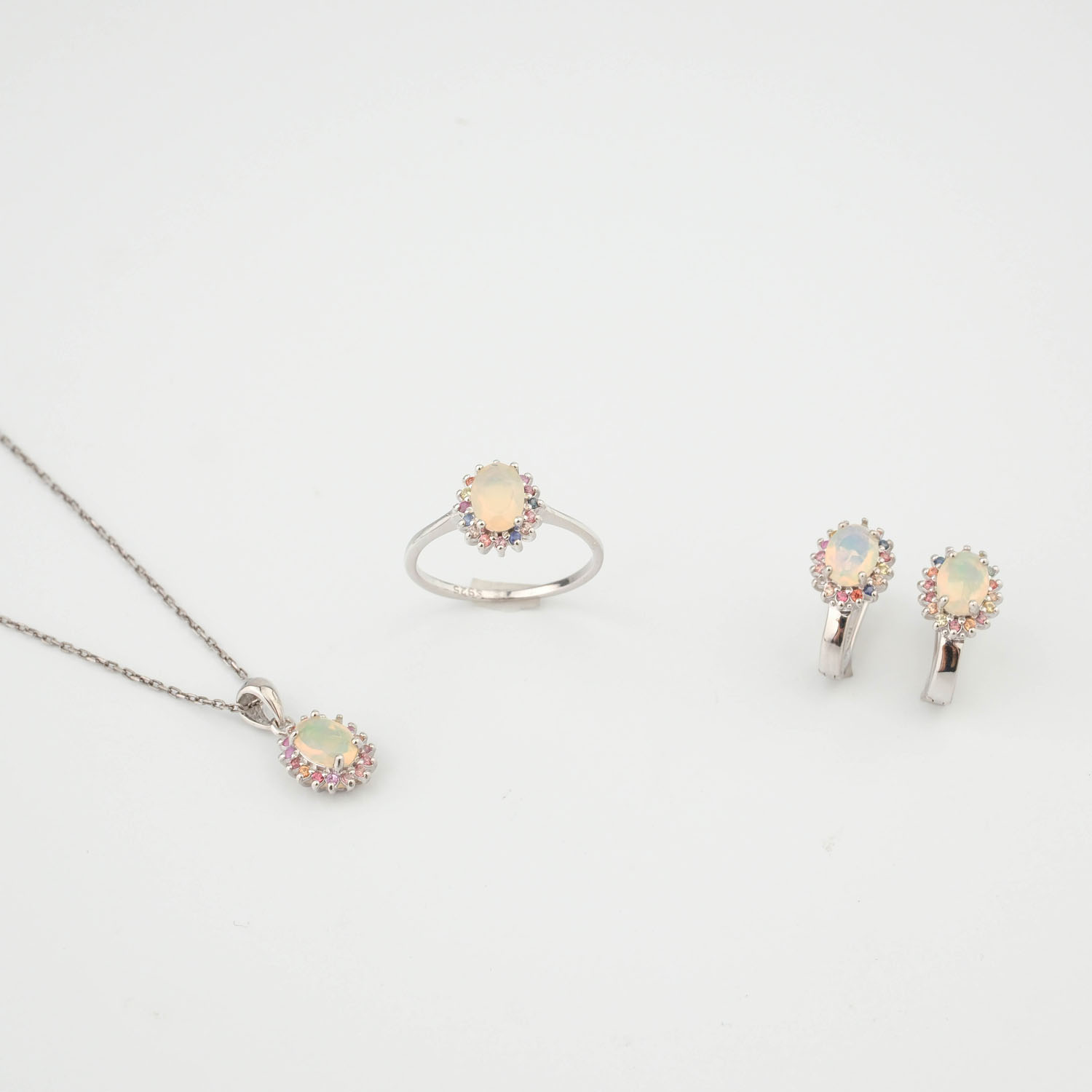 parure-luxe-pierre-naturelle-opale-et-saphir-colore-argent-925 Set di gioielli di lusso in argento sterling 925 che include anello, orecchini e ciondolo adornati con opali cabochon e zaffiri colorati.