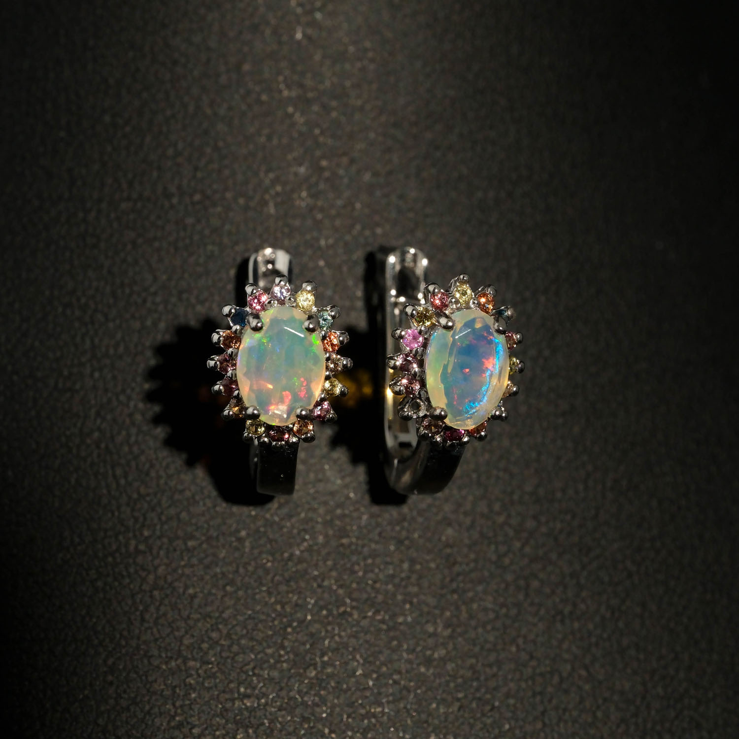 set-pietra-naturale-opale-e-zaffiro-colorato-argento-925-lusso Merkezinde oval kabaşon opal ve çevresinde faset kesim çok renkli safir taşları barındıran 925 ayar gümüş tasarım yüzük, küpe ve kolye ucu set modeli.