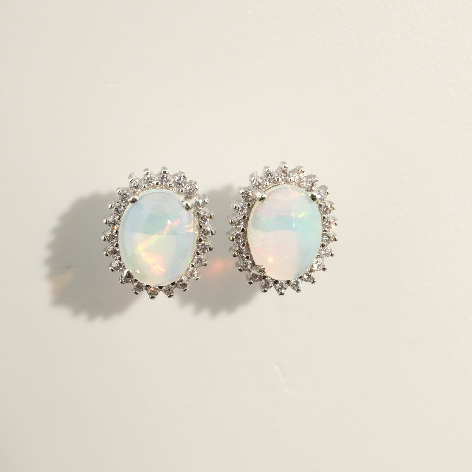 أقراط-أوبال-طبيعي-تصميم-فضة-925-فاخرة A luxury designer earrings made of original oval cabochon opal gemstones set in a 925 sterling silver halo with sparkling zircon accents.