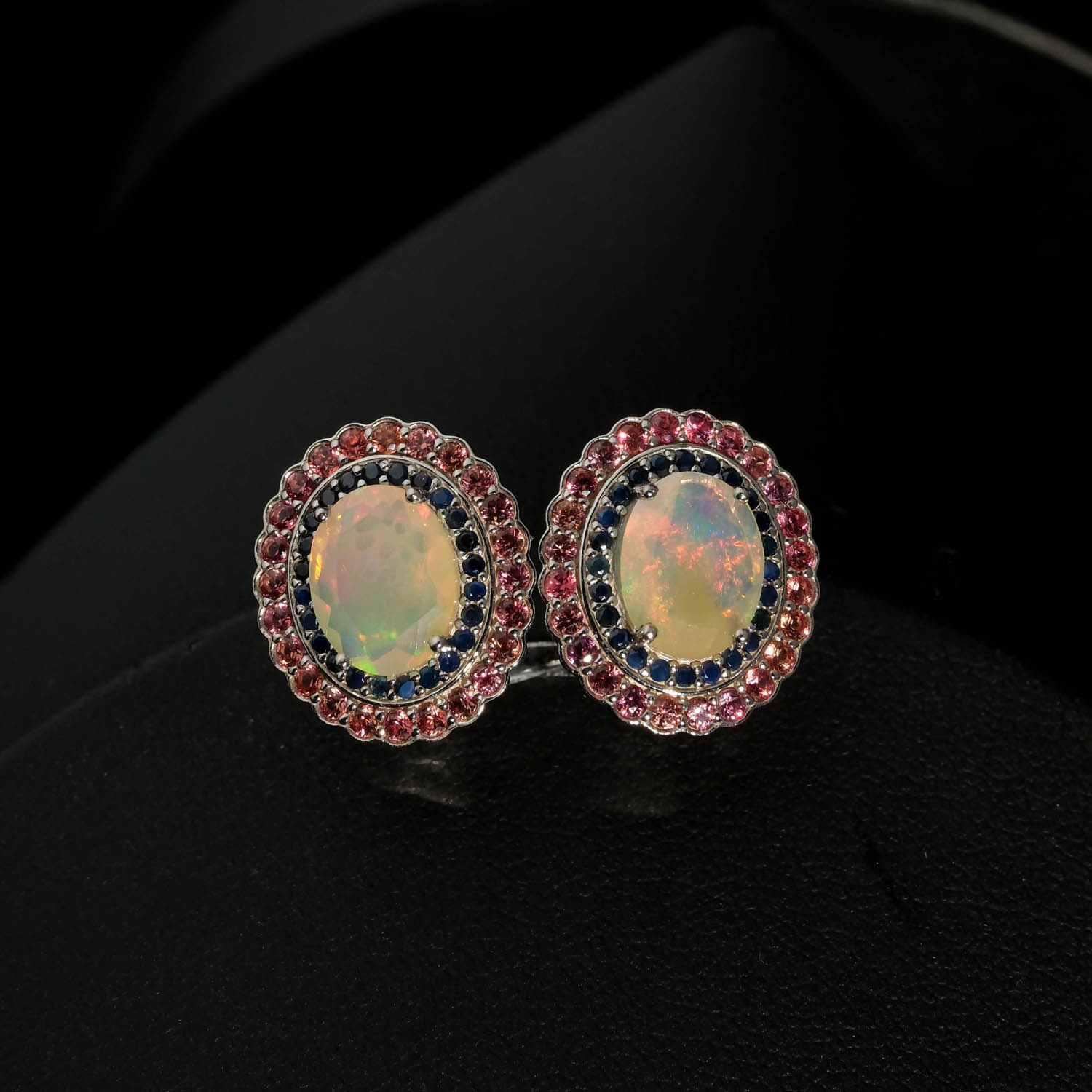 طقم-مجوهرات-أوبال-ياقوت-وجارنيت-طبيعي-فضة-925 (2) Merkezinde oval kabaşon opal, çevresinde faset kesim lacivert safir ve pembe garnet taşları barındıran 925 ayar gümüş tasarım yüzük, küpe ve kolye ucu seti modeli.