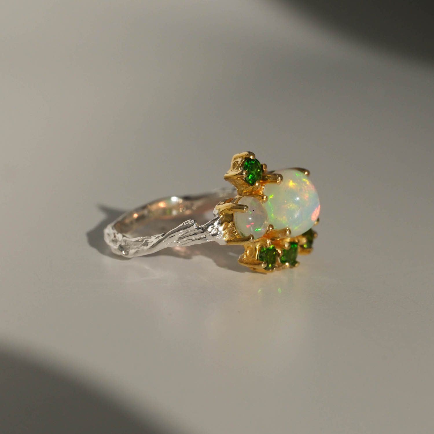 bague-luxe-pierre-opale-naturelle-et-tsavorite-argent-925 خاتم نسائي فاخر من الفضة عيار 925 بتصميم غصن شجر مرصع بحجر الأوبال الطبيعي المشع وأحجار التسافوريت الخضراء.