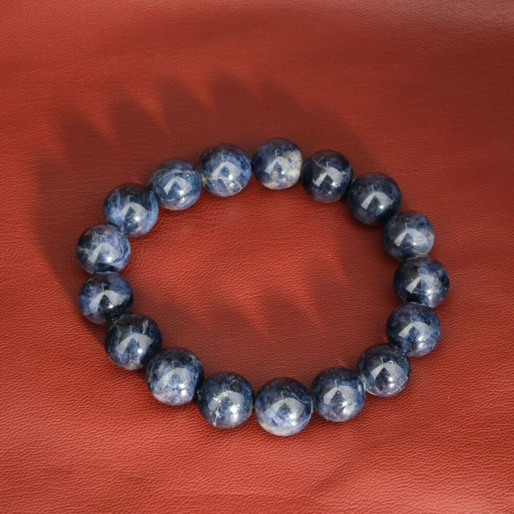A natural deep blue sapphire gemstone stretch bracelet featuring smooth 12-13mm round beads.