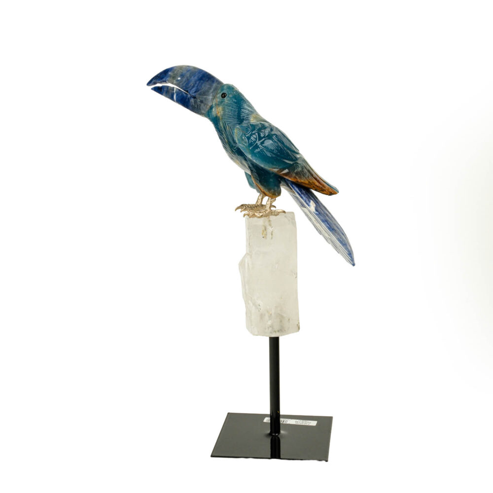A luxury hand-carved gemstone parrot sculpture made of sodalite, blue calcite, and clear quartz on a black metal stand.