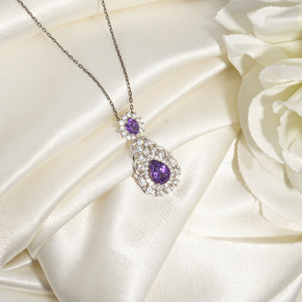 Collana da donna in argento 925 con pendente a goccia in ametista naturale viola su tessuto bianco.