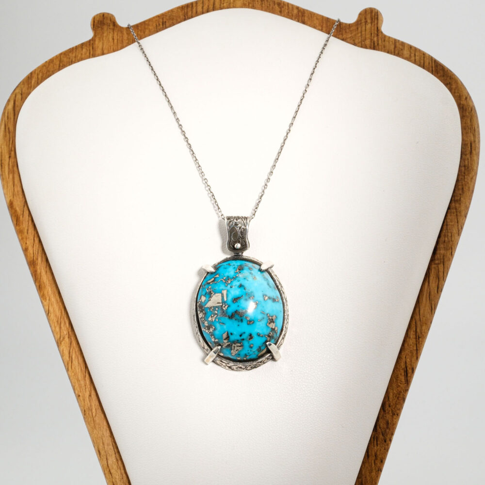 A 925 sterling silver handmade unisex pendant featuring a natural oval Nishapur turquoise gemstone with pyrite inclusions.