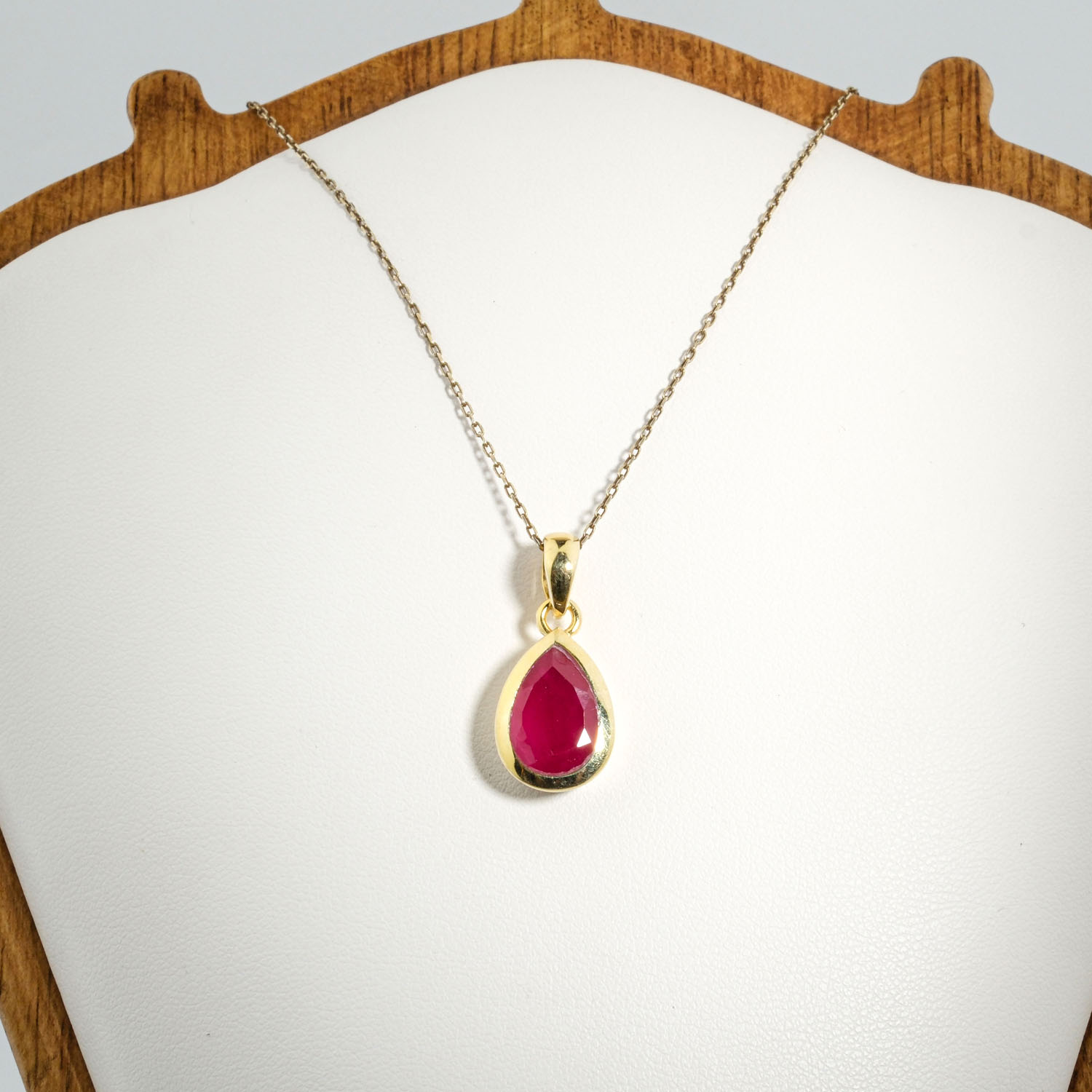 zenska-pozlacena-ogrlica-prirodni-rubin-kplja-srebro-925 A gold-plated 925 sterling silver women's pendant featuring a natural pear-shaped faceted red ruby gemstone in a bezel setting.