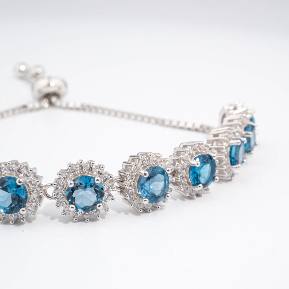 Bracelet coulissant de haute joaillerie en argent 925 avec topazes London blue naturelles et halo de zircons étincelants.