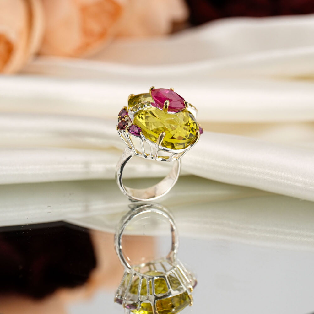 Natural large faceted lemon quartz statement cocktail ring with ruby accent, garnet, and rubellite in 925 silver on white satin.