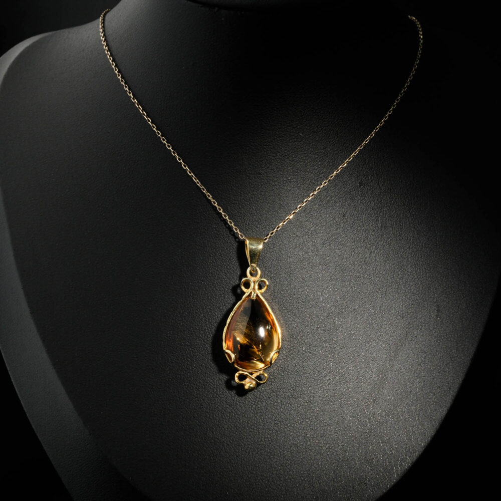 Natural faceted teardrop yellow citrine gemstone pendant necklace in 14k gold plated 925 silver on white satin.