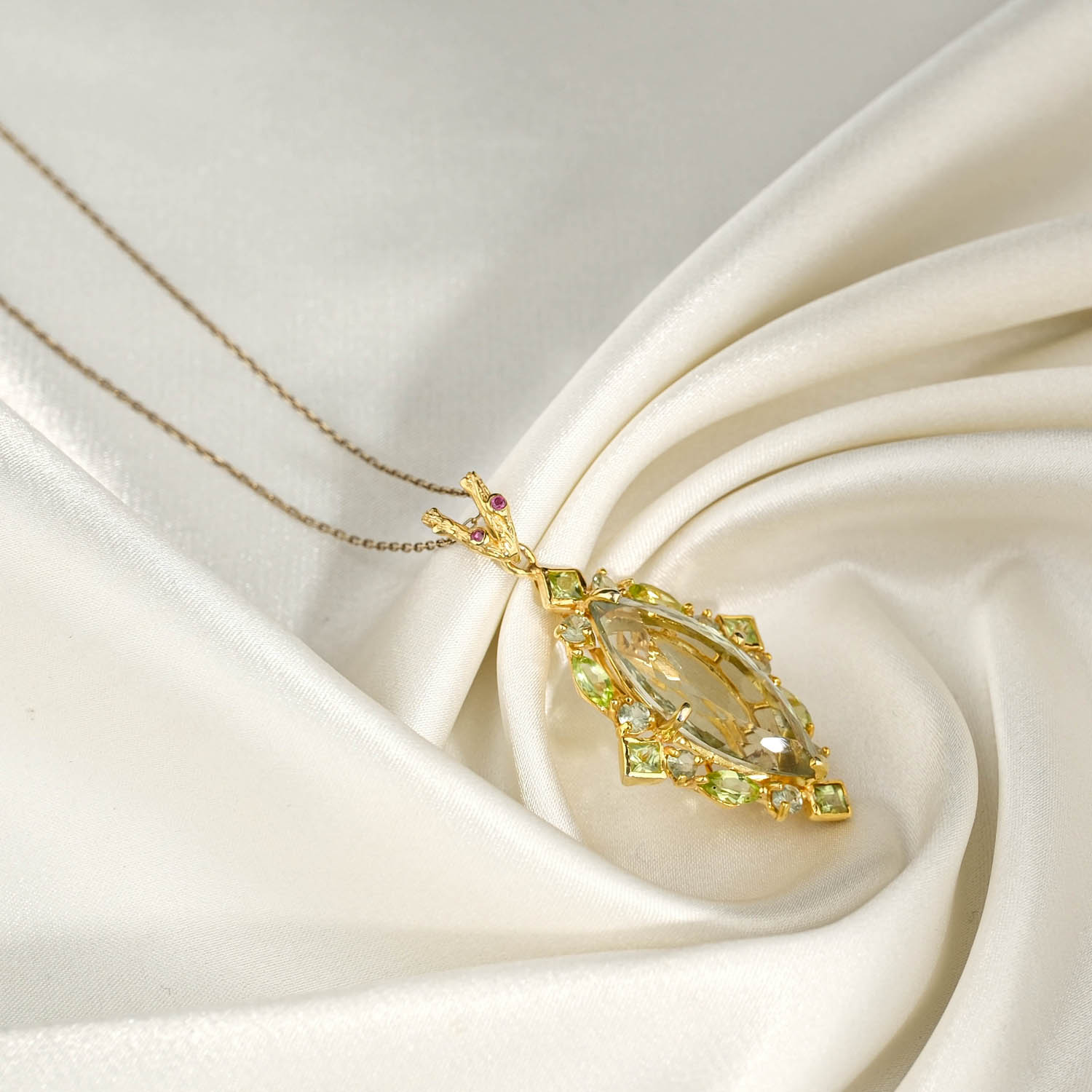 orijinal-markiz-yesil-ametist-zebercet-925-gumus-gold-kolye.jpg Beyaz saten kumaş üzerinde faset markiz yeşil ametist etrafında zebercet taşlı sarı altın kaplama 925 gümüş kadın kolye ucu ve zincir