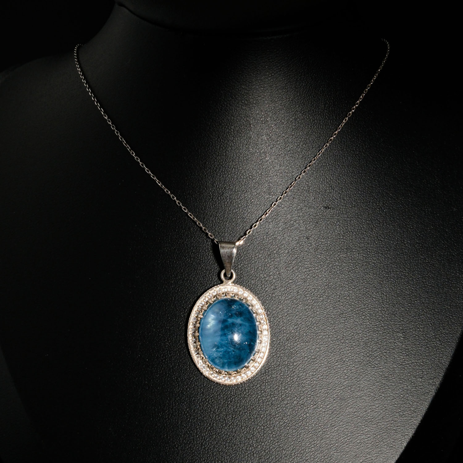 pendentif-unisexe-argent-925-aigue-marine-naturelle-ovale-halo-oxydes-de-zirconium Pendentif unisexe de prestige en argent 925 orné d'une aigue-marine naturelle bleue ovale cabochon entourée de brillants oxydes de zirconium.
